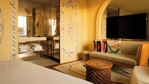 A hotel room with a large mirror, a television, a sofa, and a small round table. - 9Confidentiel (Paris)