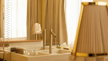 A bathroom with a large mirror, a sink with a gold faucet, and a towel rack with folded towels.