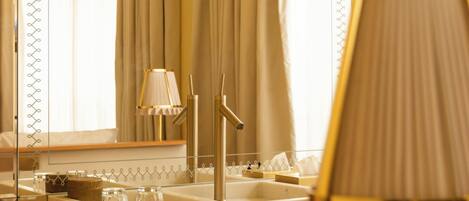 A bathroom with a large mirror, a sink with a gold faucet, and a towel rack with folded towels.
