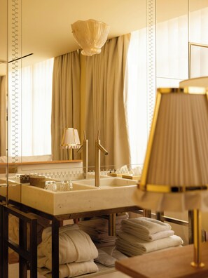 A bathroom with a large mirror, a sink with a gold faucet, and a towel rack with folded towels.