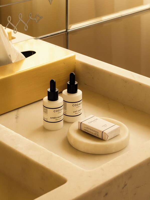 A bathroom vanity with a tissue box, two bottles of Codage Paris body lotion, and a soap bar.