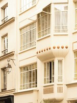 A corner of a building with multiple windows, a decorative balcony, and a street lamp.