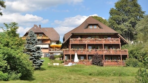 A traditional chalet-style building with multiple balconies, surrounded by lush greenery and a clear sky. - Hotel Imbery (Hinterzarten)