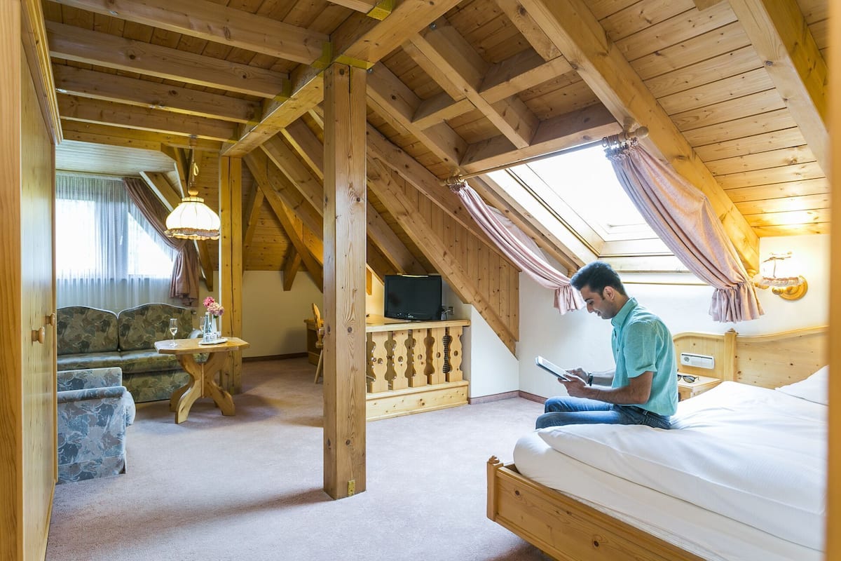 Una habitación acogedora con una cama, televisor, sofá y una mesa con lámpara.