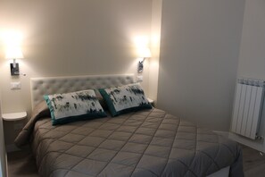 A bedroom with a bed, two wall-mounted lamps, and a radiator.