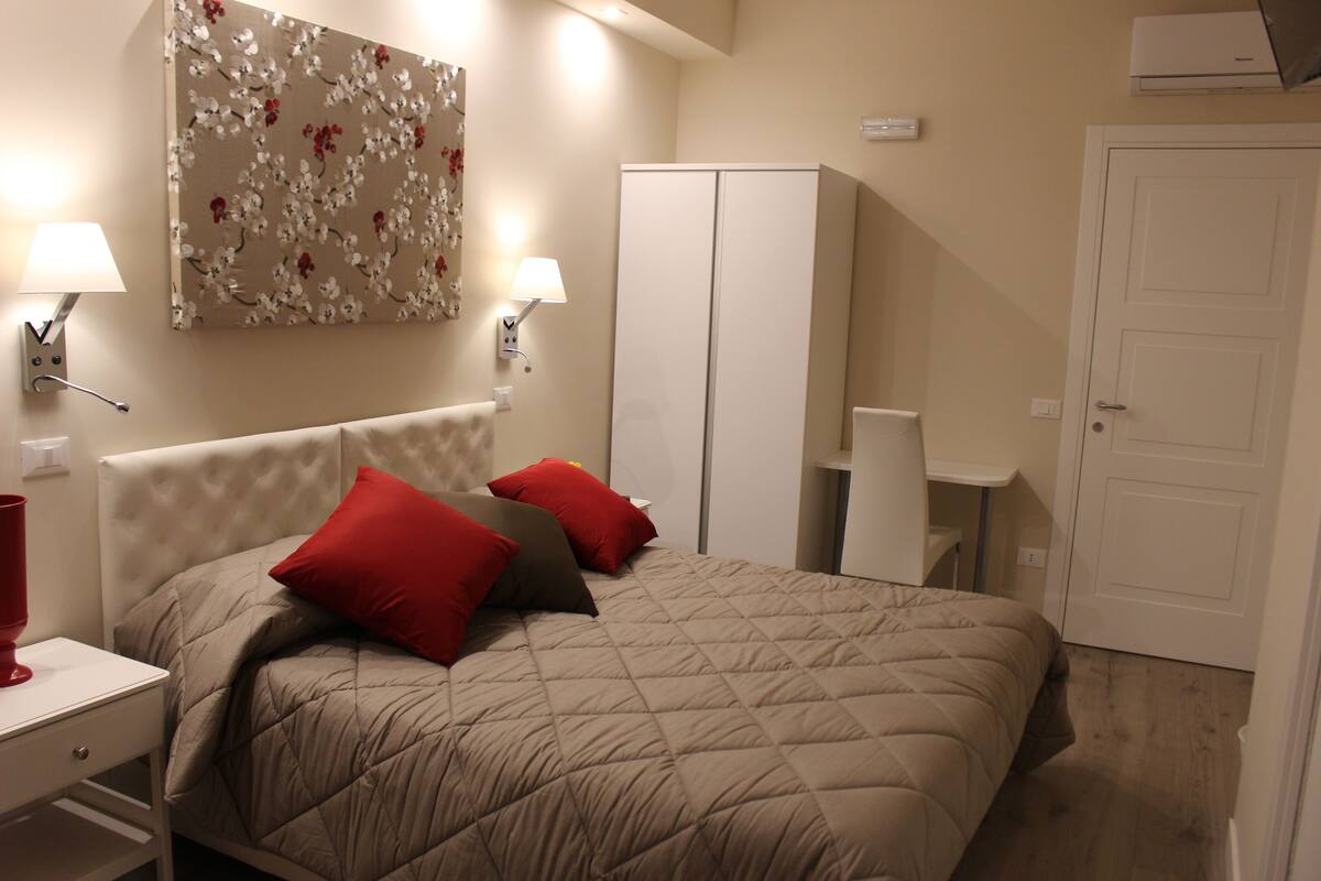 A bedroom with a bed, two nightstands, a wardrobe, and a door.
