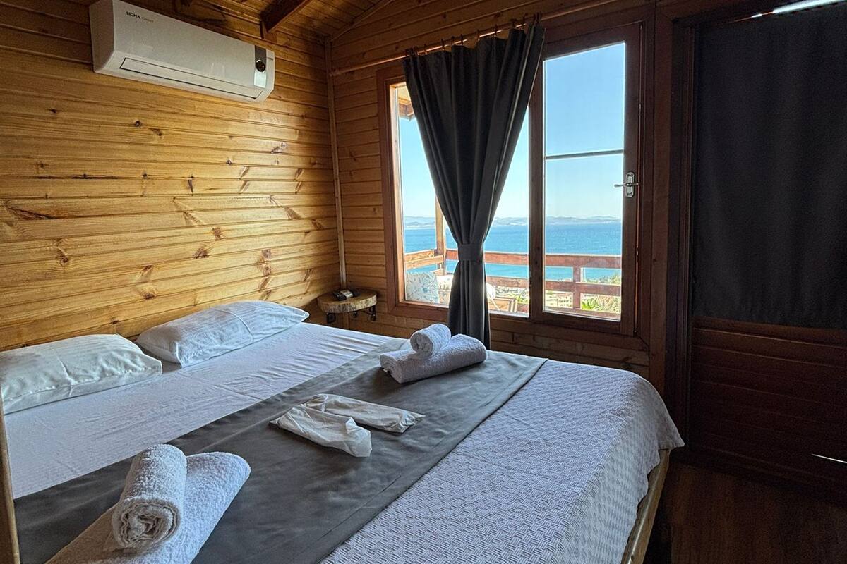 Une chambre dans un chalet en bois, avec un lit, une fenêtre donnant sur un paysage agréable et un appareil de climatisation.