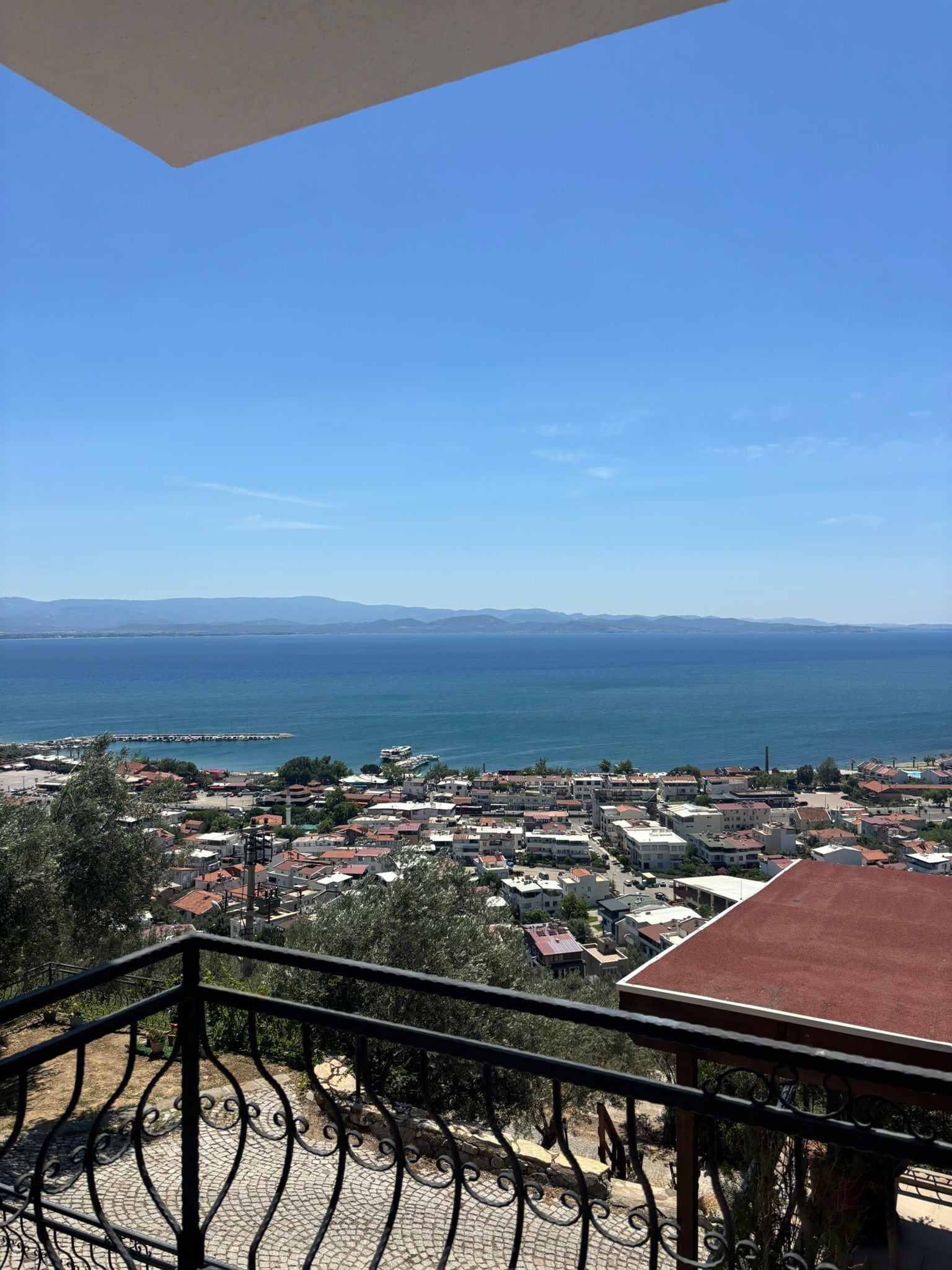 A balcony with a view of a coastal town, including buildings and the sea.
