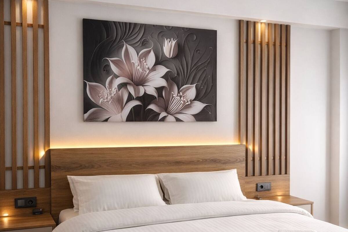 Une chambre moderne avec un grand lit, une tête de lit en bois, des tables de chevet et une œuvre d’art accrochée au mur.