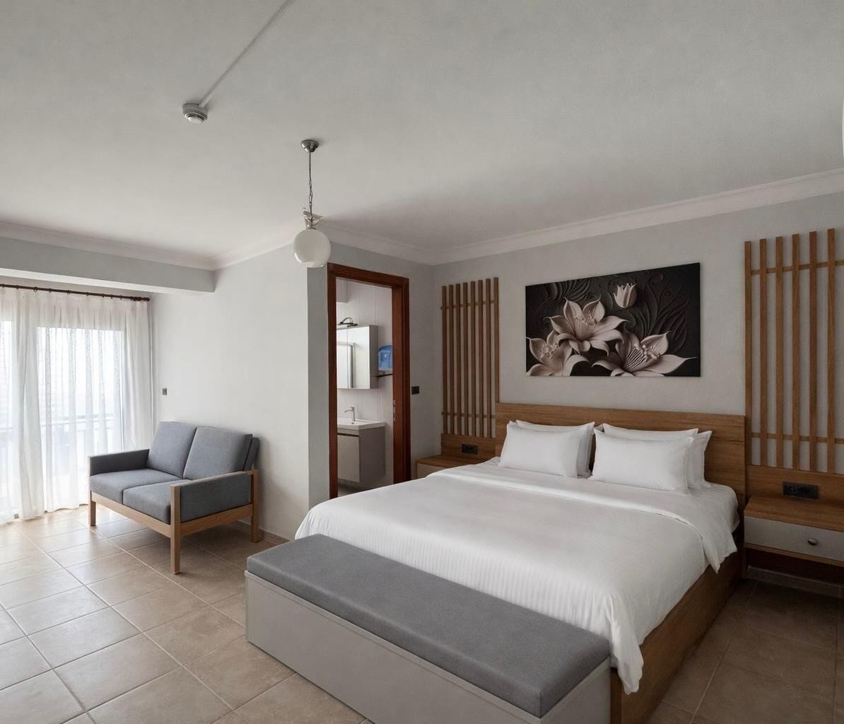 Een moderne hotelkamer met een groot bed, een zithoek, een badkamer en uitzicht op het groen.