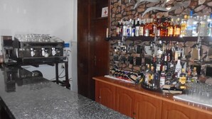 A bar area with a granite countertop, a coffee machine, and shelves stocked with various liquor bottles. - Pacific Hotel (Addis Ababa)