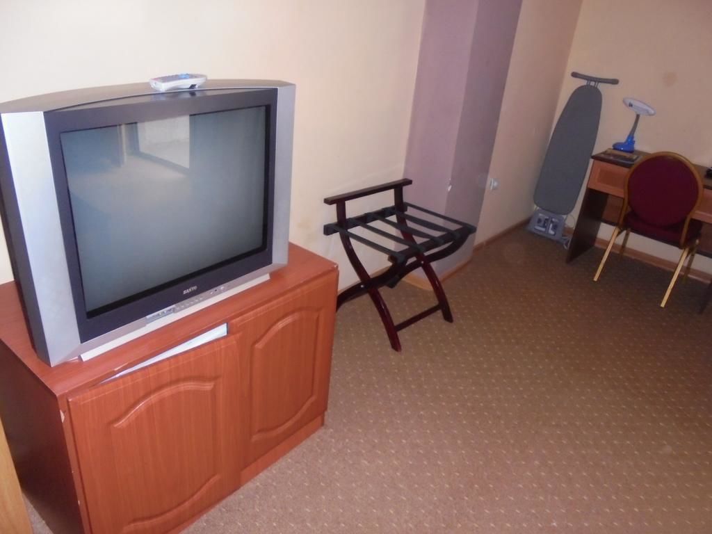 Een televisie op een houten kast, een kleine tafel met een stoel, en een skateboard tegen een muur.
