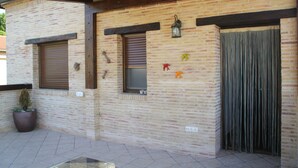 A brick building with two windows, a door, and a potted plant.