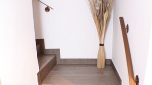 A wooden staircase with a broom in a vase at the top.