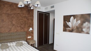 A bedroom with a bed, bedside table, lamp, wardrobe, and a framed picture on the wall.