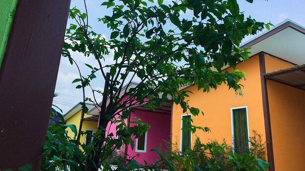 A residential area with colorful houses, a tree with green leaves, and a clear sky. - Yamsurl House Resort (Nikhom Phatthana)