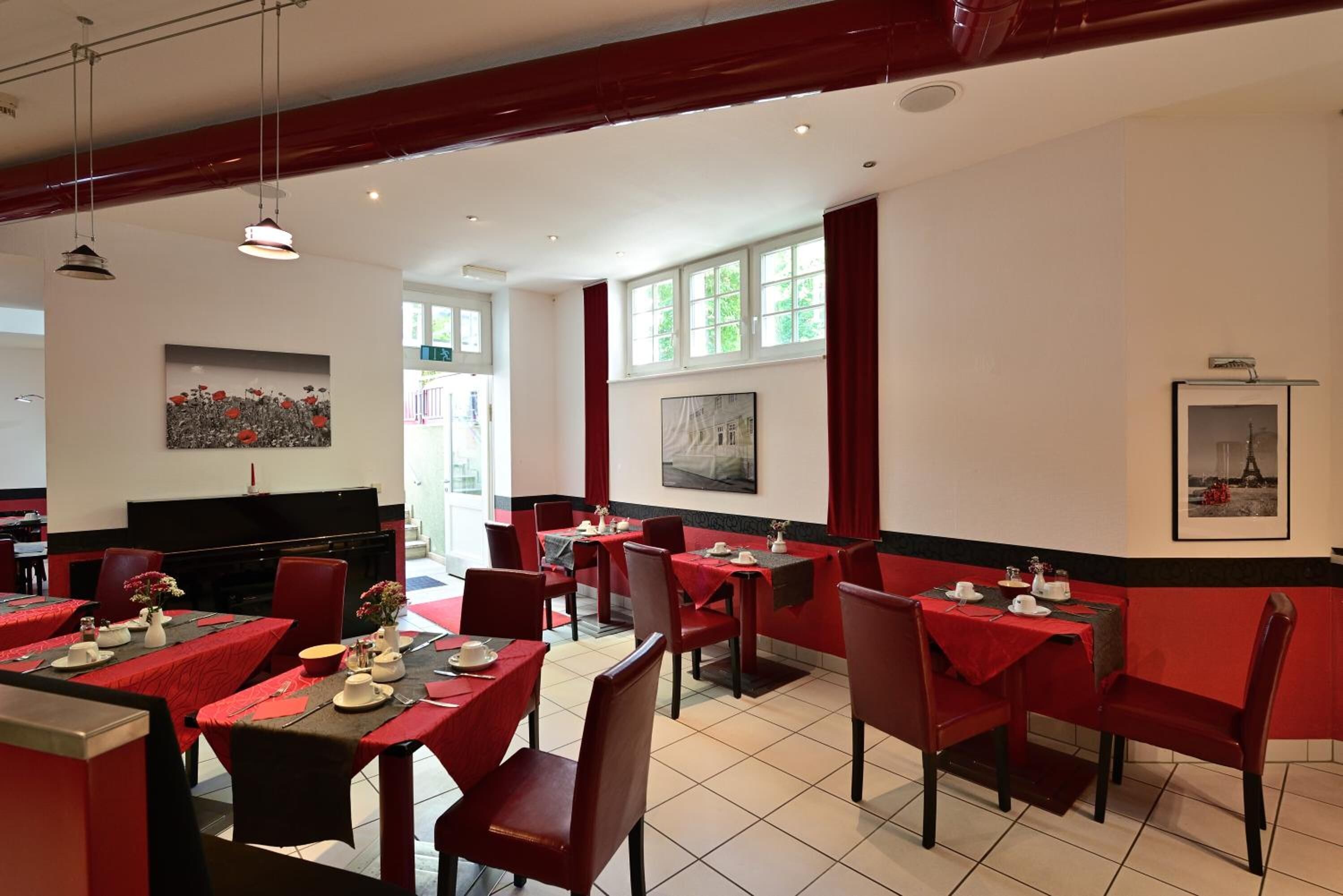 A restaurant with red and black decor, multiple tables, and chairs.