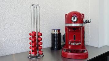 A red espresso machine and a wine rack with red bottles on a countertop.