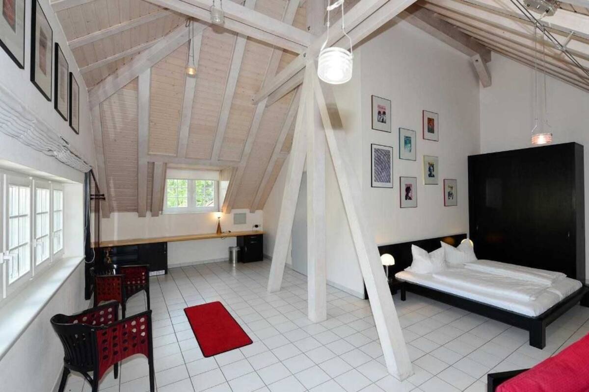 A spacious loft bedroom with a large bed, a desk, and a dining area.
