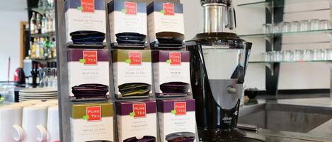 Una exhibición de cajas de té Pure Tea y una máquina de café sobre una encimera.