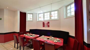 A restaurant with red and black decor, multiple tables set for dining, and large windows.