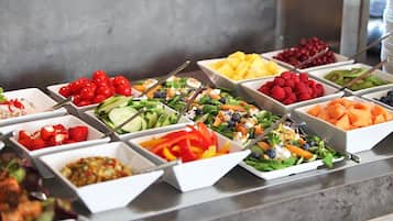 A buffet with various food options including salads, fruits, and vegetables.