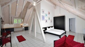 A spacious loft bedroom with a large bed, a dining area, and a kitchen. - Art Hotel Weimar (Weimar)