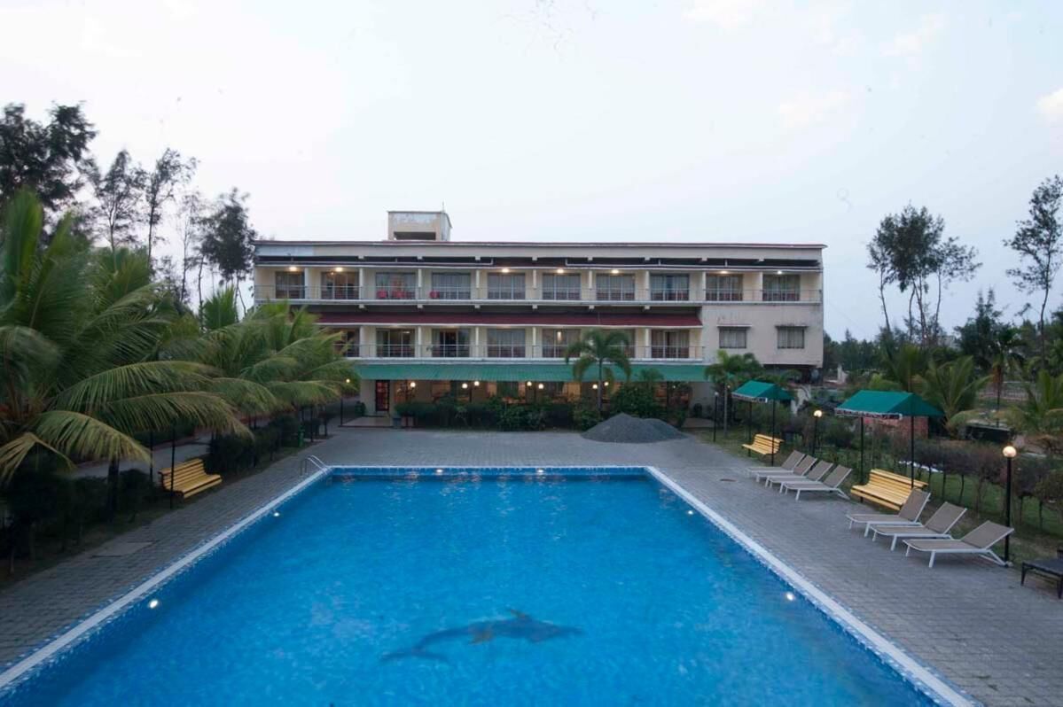 A hotel with a swimming pool, palm trees, and lounge chairs.