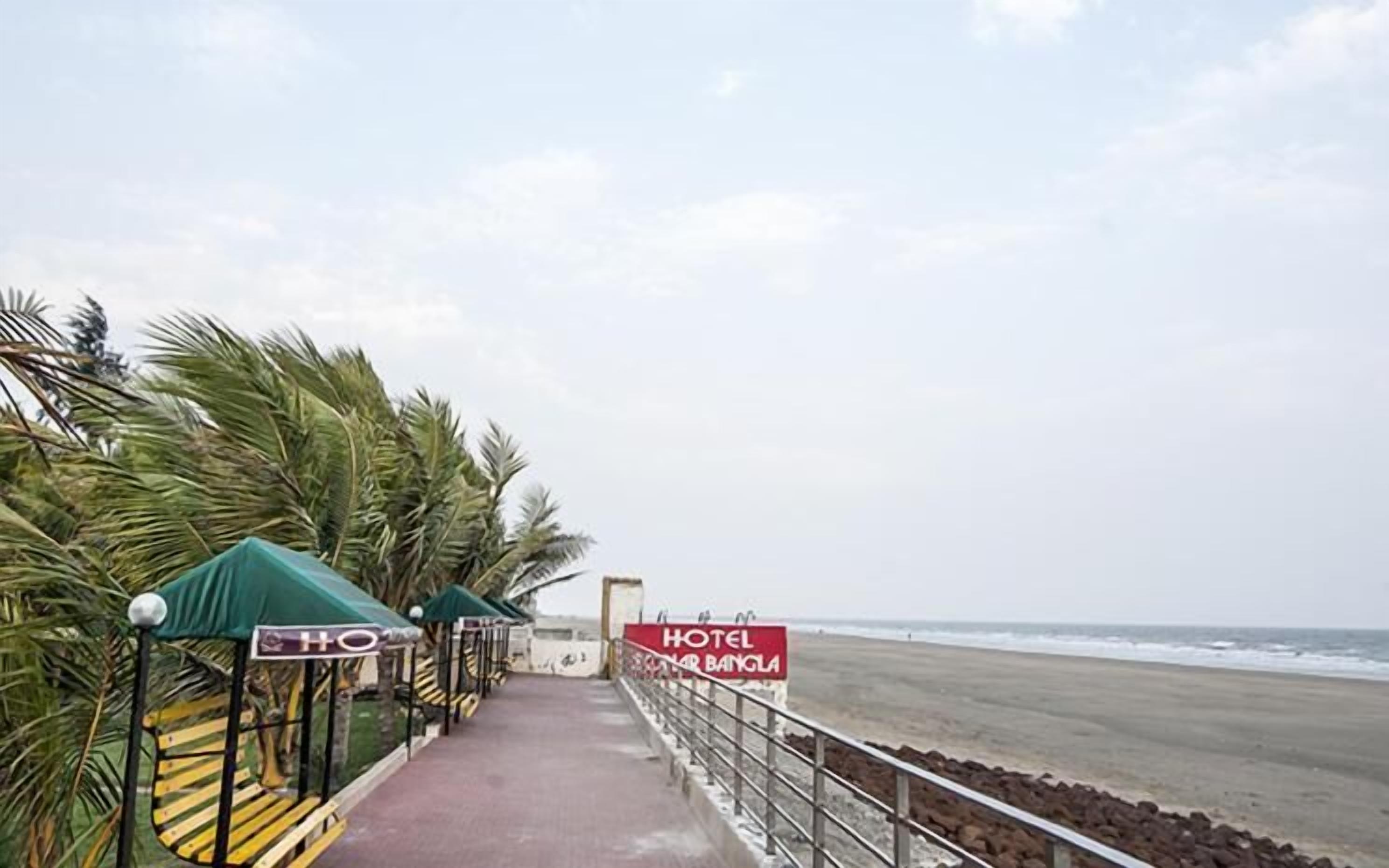 Ein Weg führt zu einem Strand mit Palmen und einem Schild für Hotel Solar Banjla.