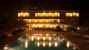 Un hôtel à plusieurs étages doté d’une piscine et d’un espace extérieur aménagé pour se détendre.