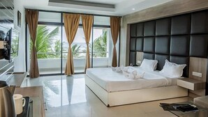 Une chambre d’hôtel moderne dotée d’un grand lit, d’une télévision à écran plat, d’une machine à café et offrant une vue sur les palmiers à travers de grandes fenêtres.