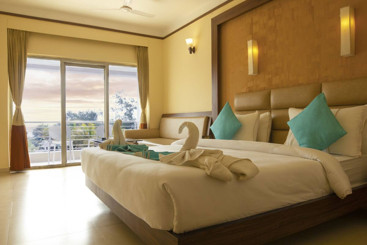 Een hotelkamer met een groot bed, een balkon en een uitzicht, plus een plafondventilator.