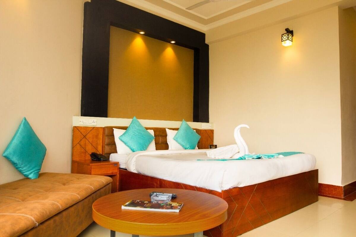 Een hotelkamer met een bed, een bank, een ronde tafel en een wandlamp.