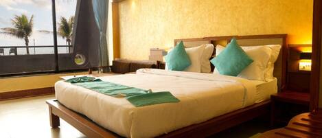 A hotel room with a large bed, wooden headboard, and a view of palm trees through a window.