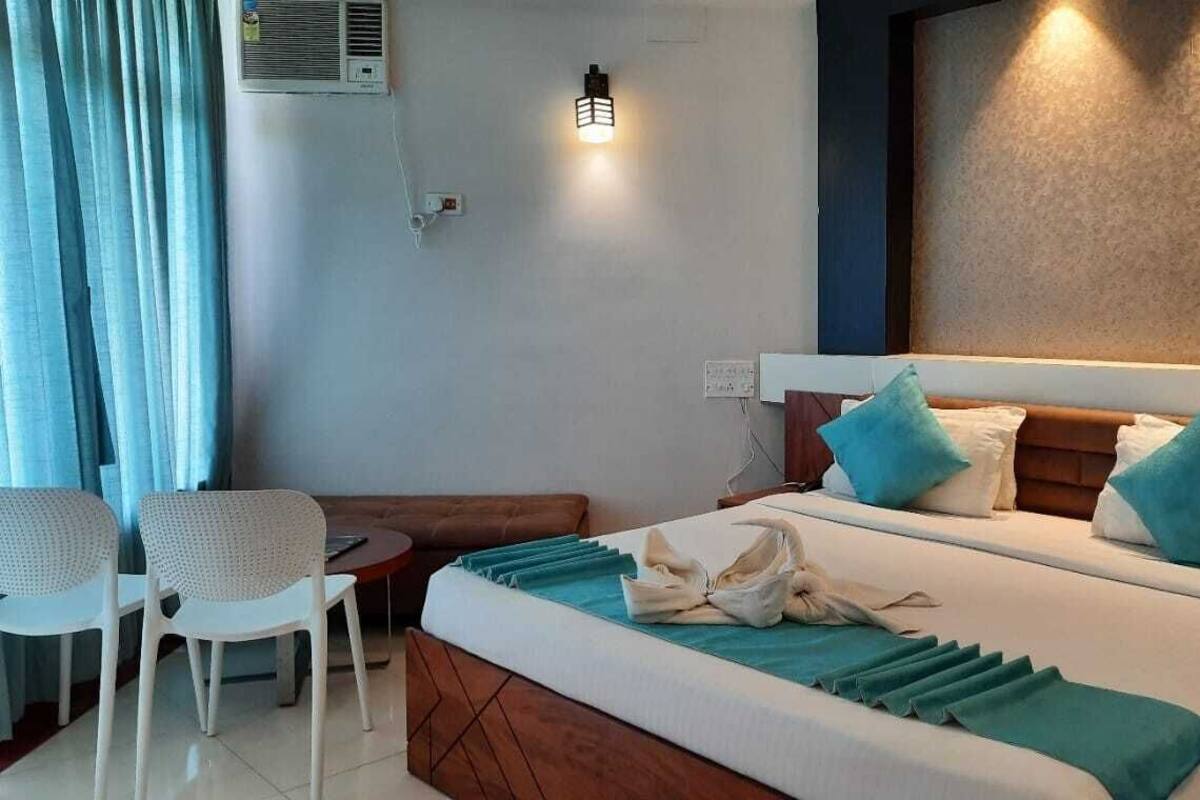 Een hotelkamer met een bed, een tafeltje, twee stoelen en een wandairconditioner.