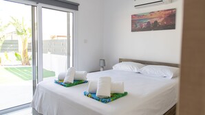 Une chambre d’hôtel avec un grand lit, une vue sur l’extérieur, un appareil de climatisation et un tableau au mur.