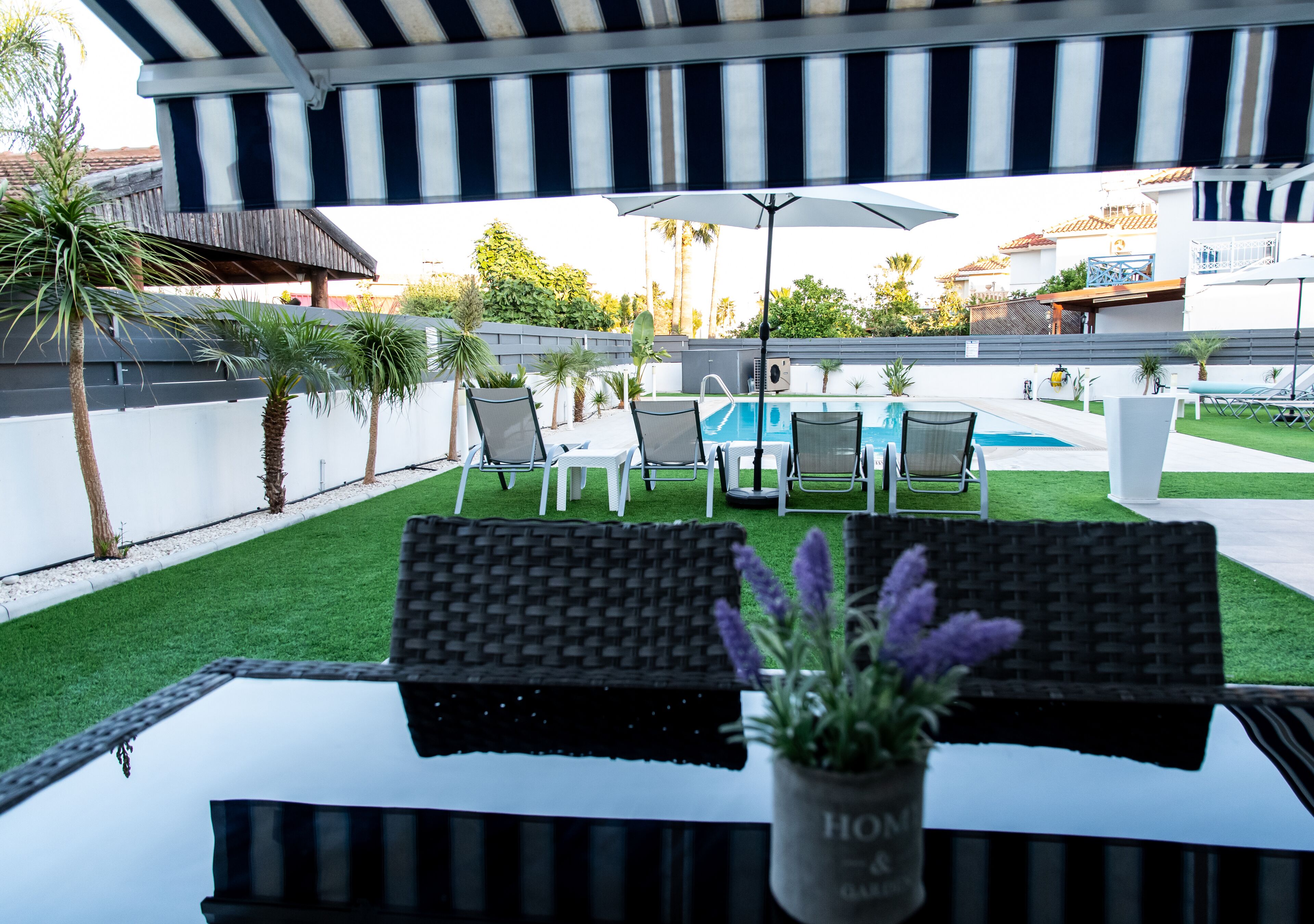 A poolside area with a covered seating area, a pool, and a view of the surrounding buildings.