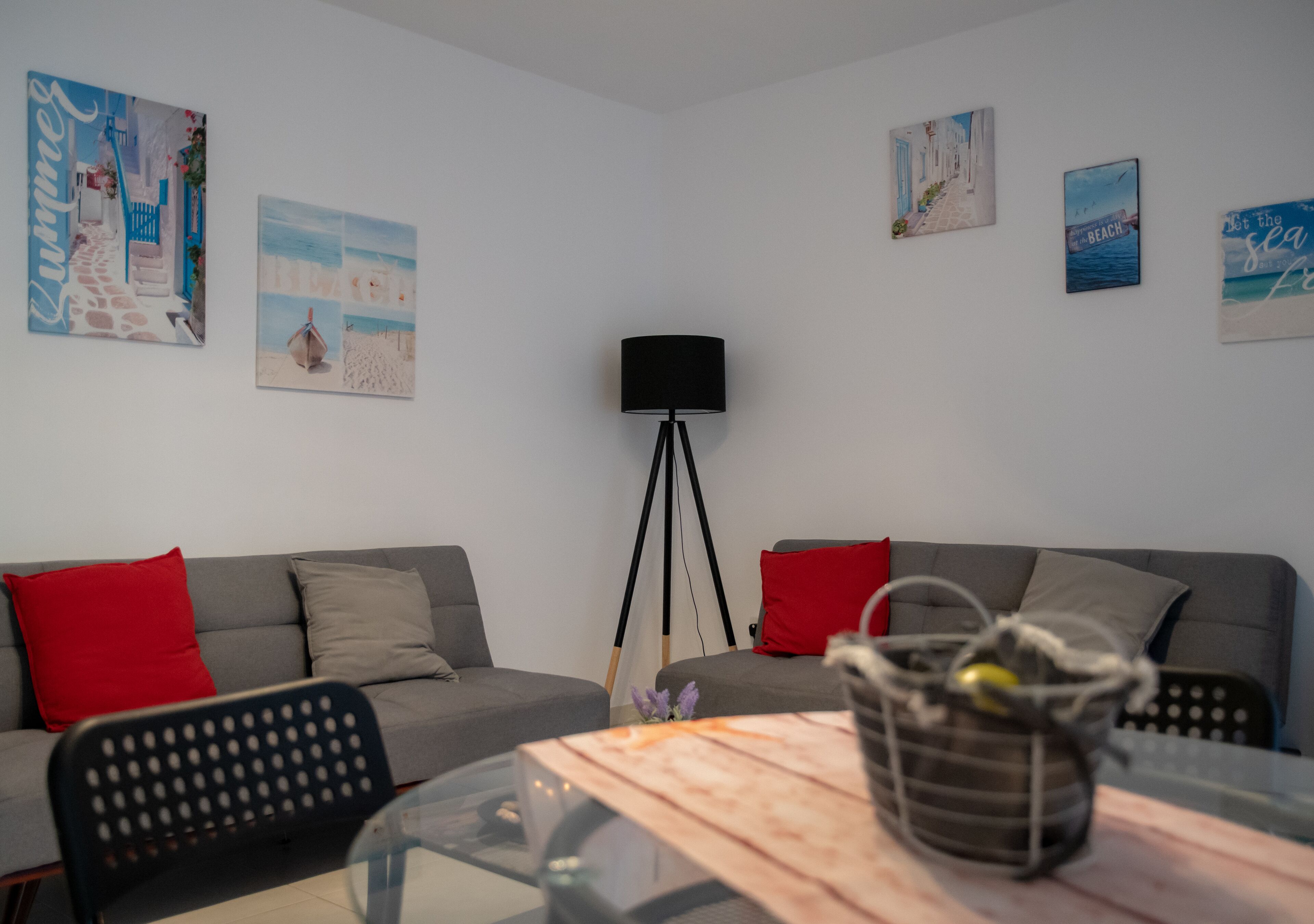 Ein modernes Wohnzimmer mit zwei grauen Sofas, einem Glastisch und einer Stehlampe.