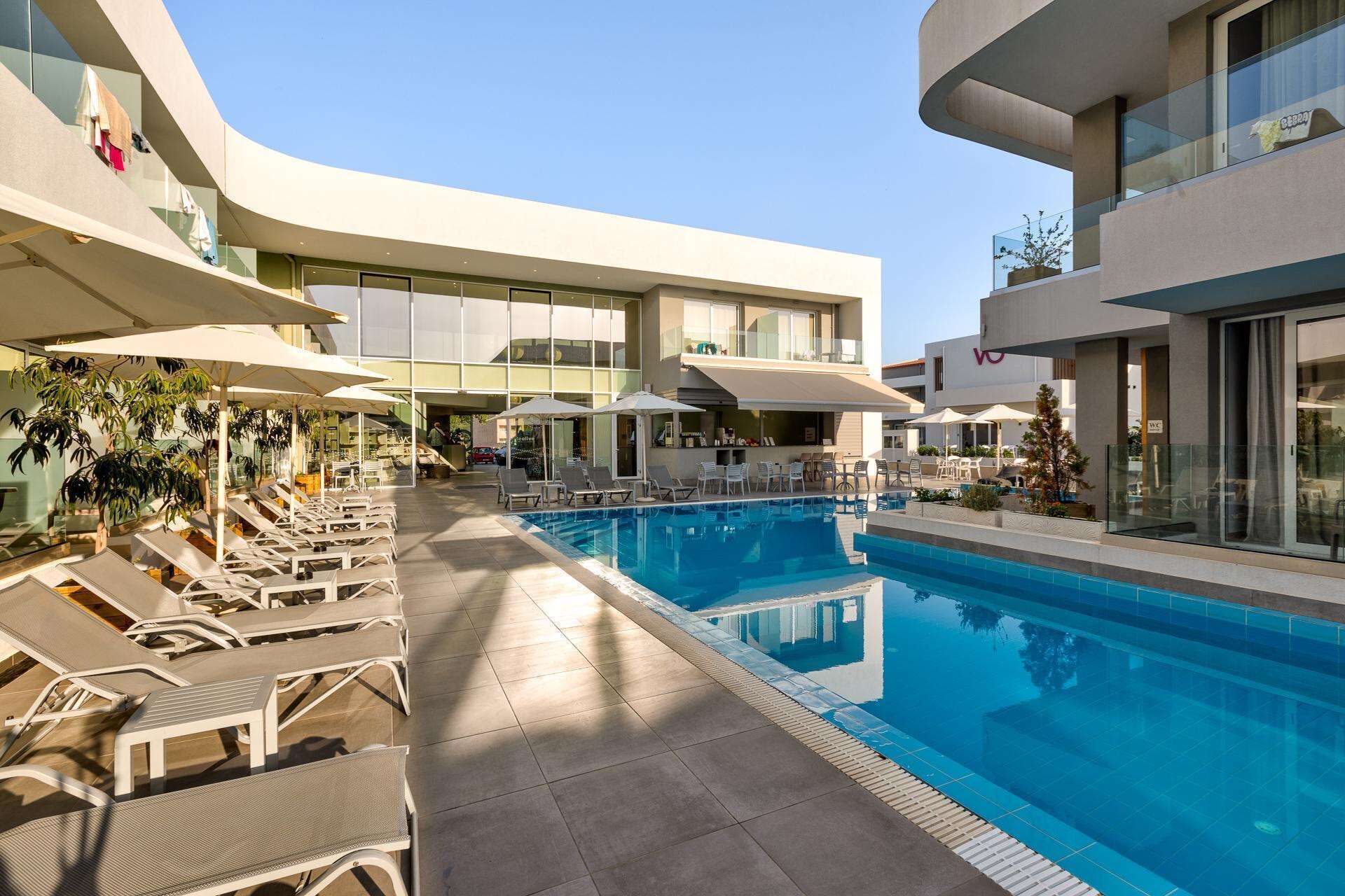 Ein modernes Hotel mit zentralem Pool, Liegestühlen und Sitzbereichen im Freien.