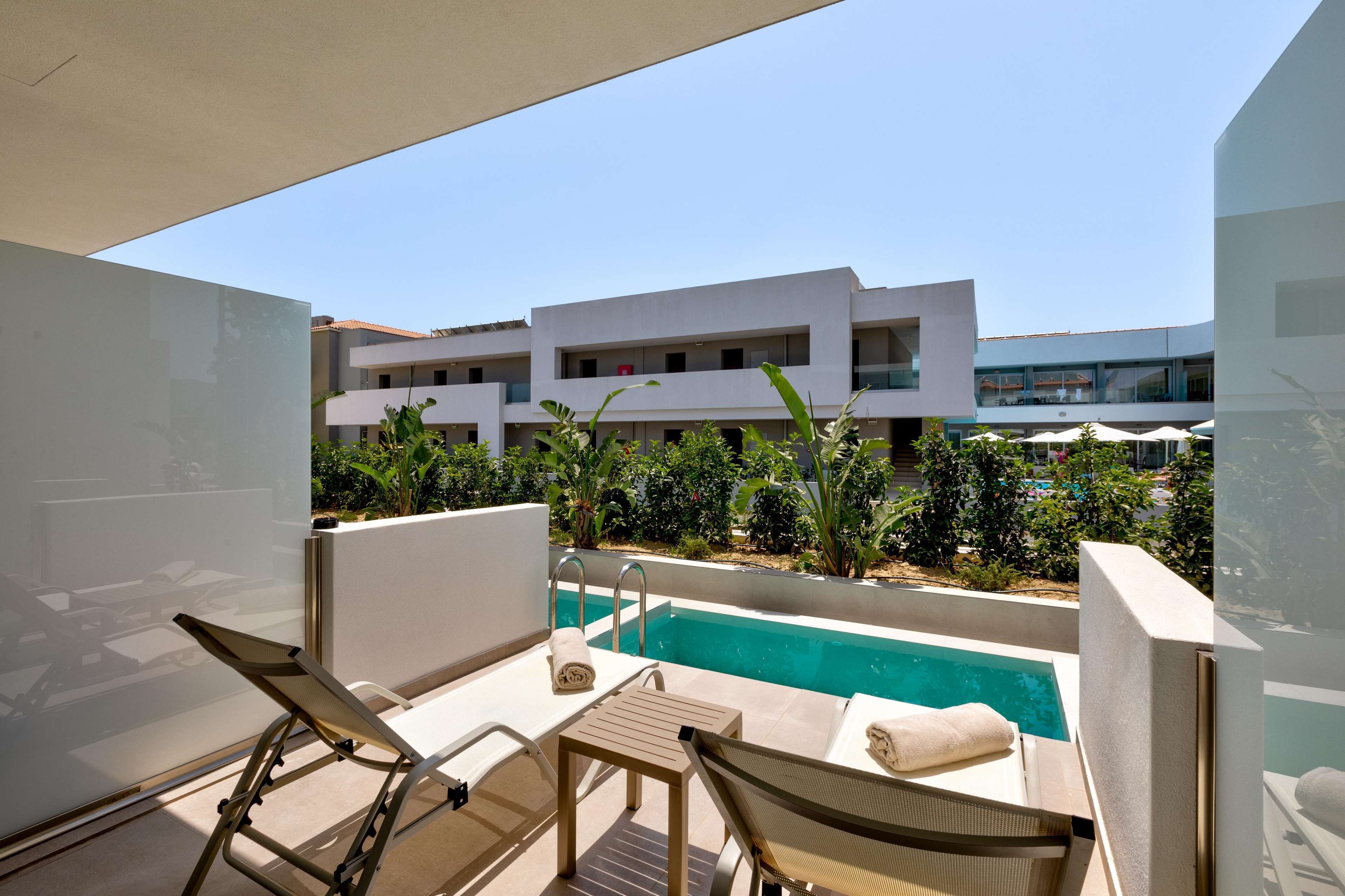 Un balcone con piscina, sedie a sdraio e vista su un edificio moderno.