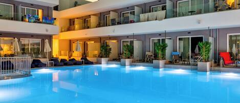 A multi-level hotel with a central swimming pool, balconies with glass railings, and outdoor seating areas.