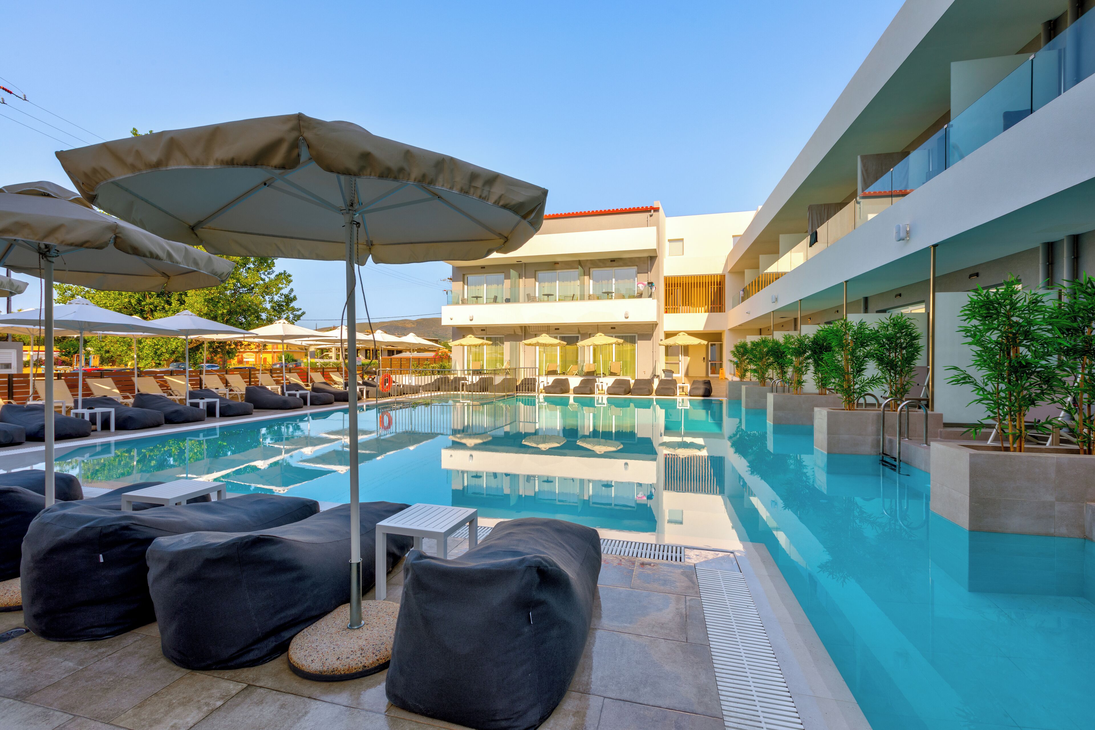 A modern hotel pool area with lounge chairs, umbrellas, and a clear blue pool.
