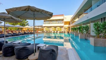 A modern hotel pool area with lounge chairs, umbrellas, and a clear blue pool.