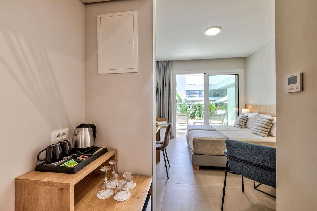 A hotel room with a kitchenette, a sofa bed, a dining area, and a view of the outside.
