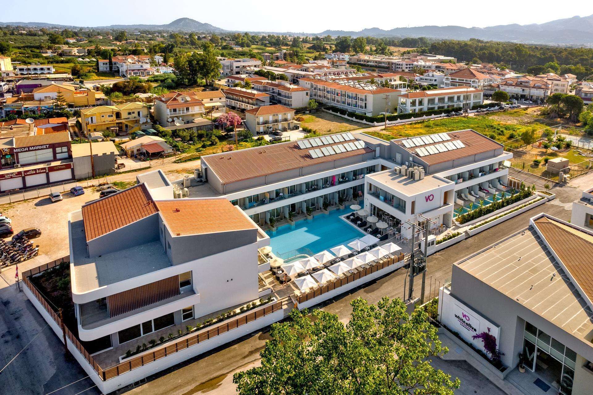 Ein modernes Hotel mit Dachpool, mehreren Etagen und Blick auf die umliegende Wohngegend.