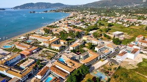 An aerial view of a coastal town with buildings, a beach, and a marina. - White Olive Premium Laganas - All Inclusive (Zakynthos)