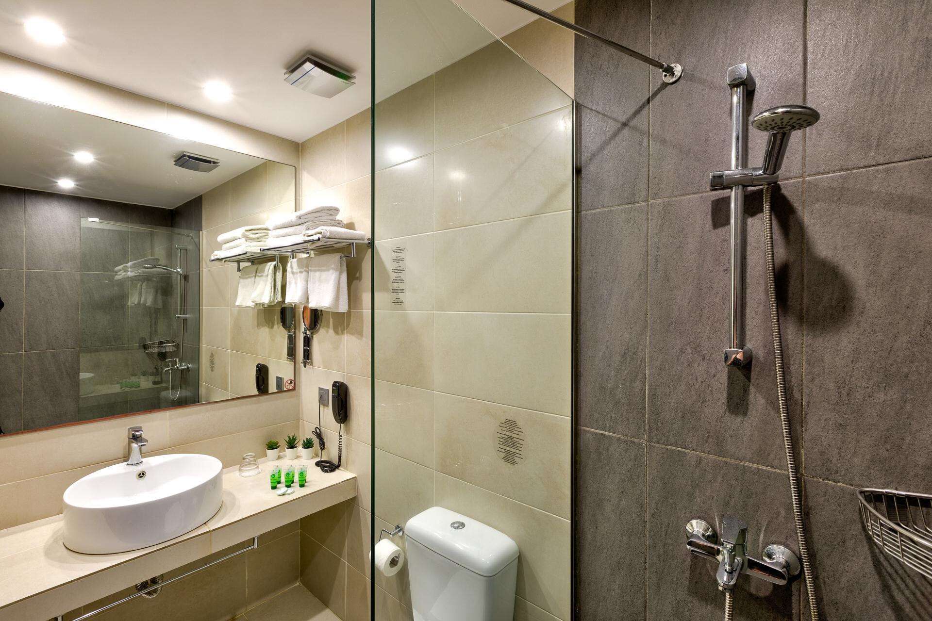 A modern bathroom with a glass shower enclosure, a sink with a mirror, and a toilet.