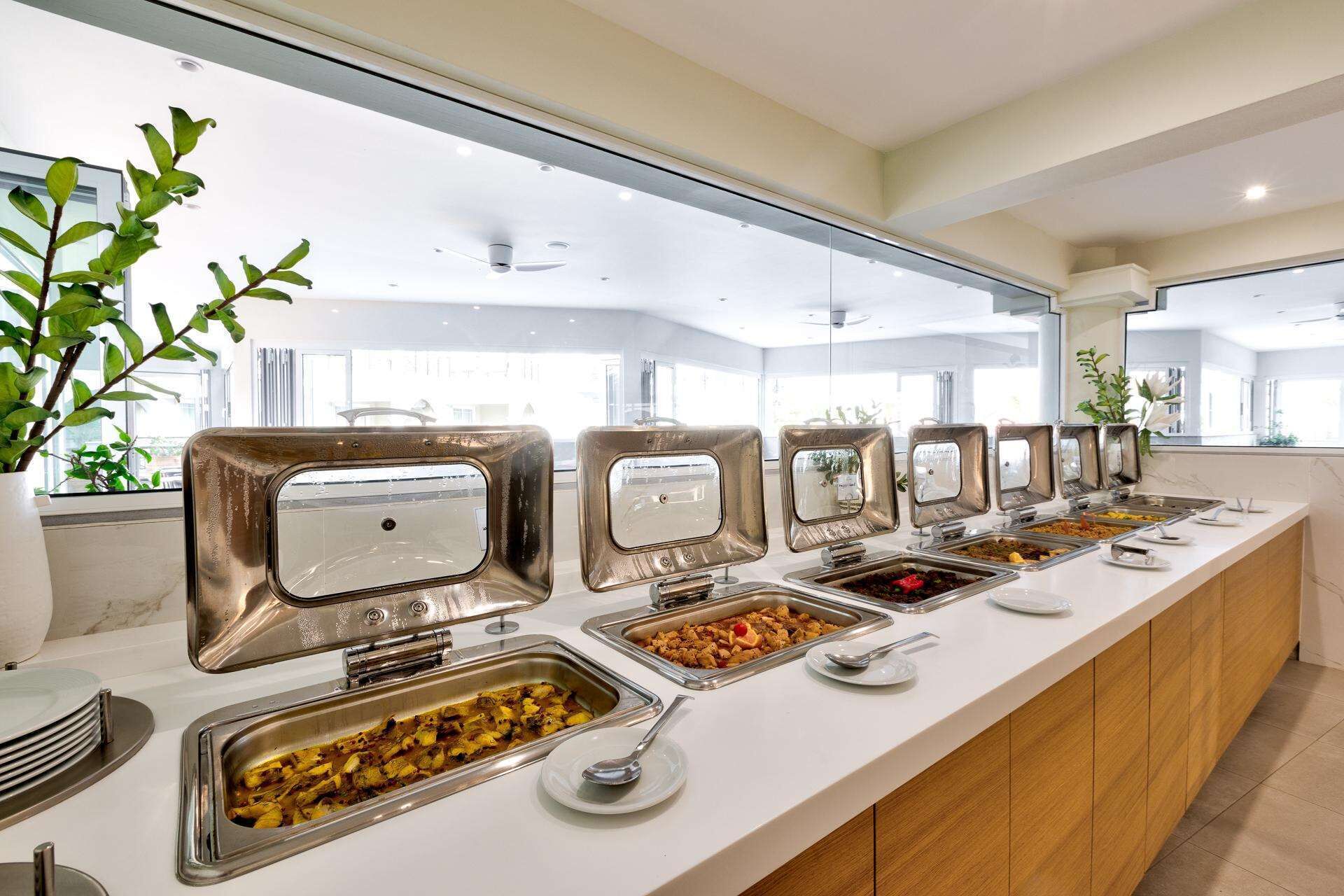Uma mesa de buffet com várias estações de comida e um balcão comprido.