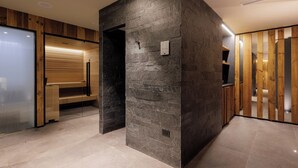 A modern interior with a stone accent wall, wooden paneling, and a glass partition. - Hotel Centrale (Pejo)