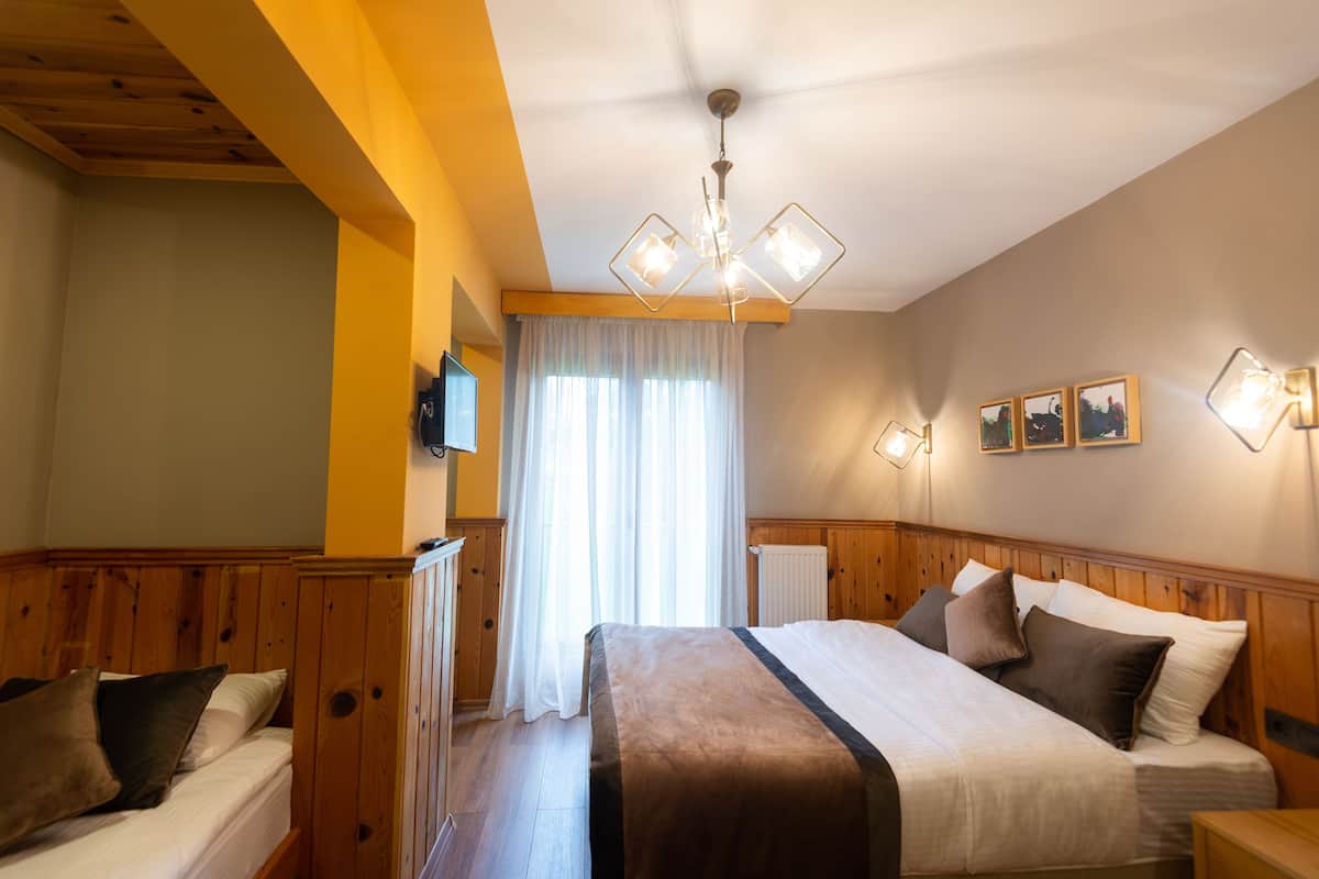 A bedroom with a wooden headboard, a large bed with multiple pillows, a ceiling fan, and a window with curtains.